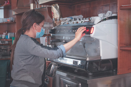 Caucasian barista wearing a protective face mask making coffee