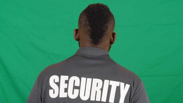 A rearview of male security personnel with a mohawk hairstyle against a green wall in HD