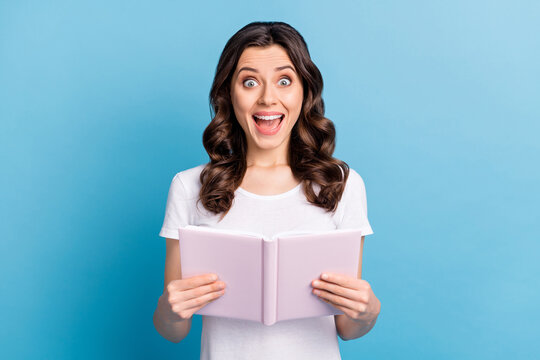 Photo of young excited girl happy positive smile read book information amazed shocked news isolated over blue color background