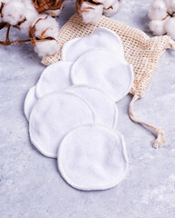 Reusable organic cotton makeup remover pads in bag on marble background