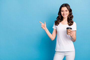 Photo of charming cute lady dressed white outfit smiling drinking coffee pointing finger empty space isolated blue color background