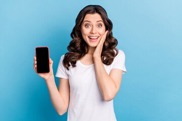Photo of excited pretty woman wear white t-shirt holding modern device empty space arm cheek isolated blue color background