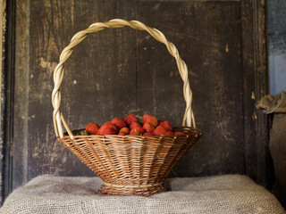 A basket of freshly picked strawberries with wooden background.