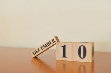 December 10, Date design with calendar cube on wooden table and white background.