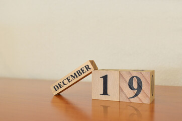 December 19, Date design with calendar cube on wooden table and white background.