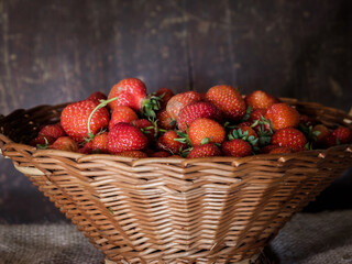 A basket of freshly picked strawberries with wooden background.