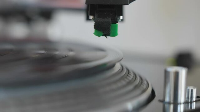 The gramophone needle slowly going down on the disc turning around