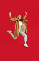 Young happy girl jumping isolated over red studio background with copyspace for ad. Concept of beauty, fashion.