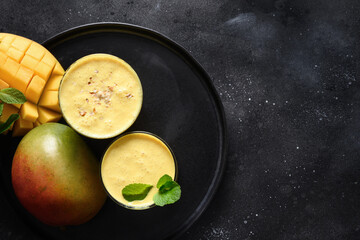Indian traditional cold mango lassi or smoothies on black background, top view with copy space....