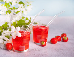 Strawberry cold refreshment lemonade with ice cube. White apple blossoms on the background. Spring concept.