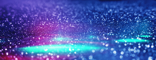 Blurred dark abstract background with glittering lights, bokeh. Ultraviolet glittering lights, sparks.