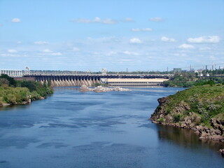 Panorama of the blue surface of the old Dnieper riverbed on the background of the dam of the Dnieper hydroelectric power plant. 