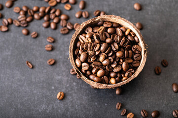 black coffee beans arabica, aromatic in a coconut bowl, sprinkled beans on the table