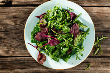 salad mix of fresh herbs, arugula, Swiss chard, spinach in tarenle on a wooden background, serhu view