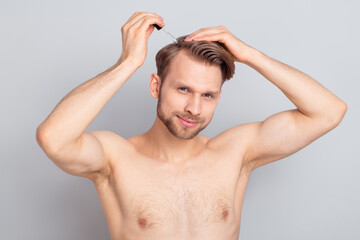 Photo of cheerful young blond man brush hair without clothes isolated on grey color background