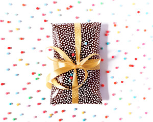 The gift is packed with wrapping paper and tied with a yellow ribbon on a white background. The concept of preparing a gift for a holiday, birthday, anniversary. Flat lay. Top view. Copy space.
