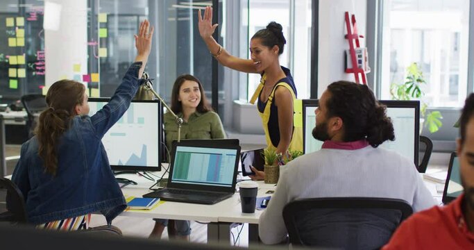 Diverse group of work colleagues giving high five and smiling