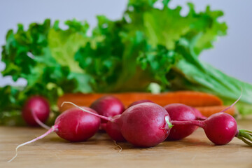 Radish, carrot, and lettuce on a wooden kitchen table 