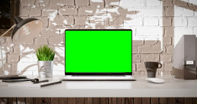 Laptop green screen zoom in and smooth camera stop. Loft office interior with brick wall and swaying trees on the wind. The last 200 frames are looped