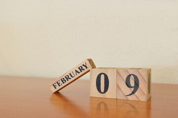 February 9, Date design with calendar cube on wooden table and white background.