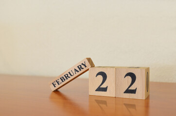 February 22, Date design with calendar cube on wooden table and white background.