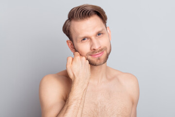 Photo of shirtless blond hairdo guy touch beard without clothes isolated on grey color background