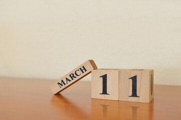 March 11, Date design with calendar cube on wooden table and white background.