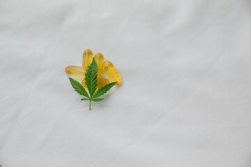 Bright yellow cbd pills and fresh marijuana leaves.  Copy space.