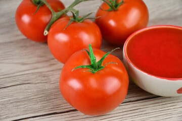 Fresh tomatoes and tomatoe paste on a wooden table.
