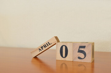 April 5, Date design with calendar cube on wooden table and white background.