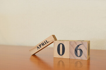 April 6, Date design with calendar cube on wooden table and white background.