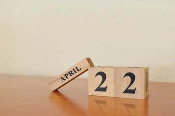 April 22, Date design with calendar cube on wooden table and white background.