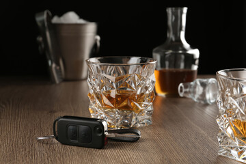 Glass of alcohol and car key on wooden table. Drunk driving concept