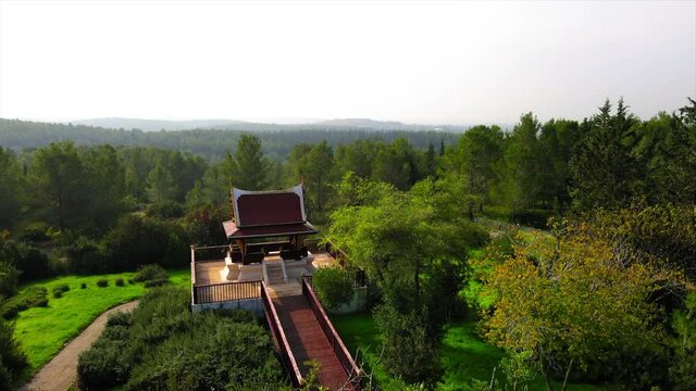 Aerial Panning Shot Of Pathway Leading Towards Pagoda, Drone Flying Over Ben Shemen Forest Against Clear Sky