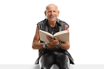 Bald man reading a book on a panel and smiling at the camera