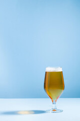 Refreshing beer in a glass on a blue background with a hard shadow. Copy space.