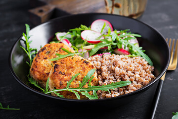 Healthy dinner. Lunch bowl with buckwheat porridge, fried chicken cutlets and fresh vegetable salad of arugula, cucumber and radish.