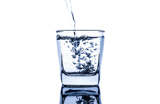 Pour water into a clear glass with a splash of water. Isolated on white background