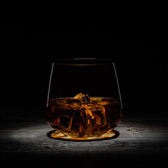 golden whiskey with ice on a wooden table