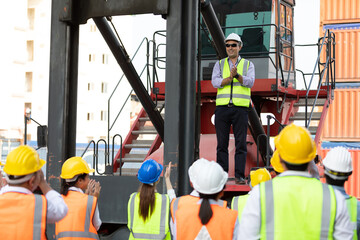 warehouse boss engineer standing on crane car with factory workers clapping hands for...
