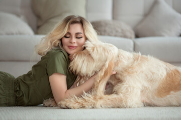 young beautiful woman with cute spinosa dog in the room. She wears vet uniform