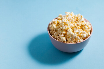 Homemade popcorn in Minsk on a blue background with a hard shadow. Copy space.