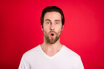 Photo of impressed young brown hairdo man look camera wear white t-shirt isolated on vivid red color background