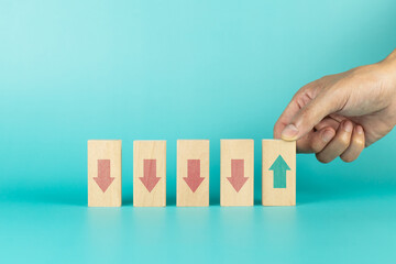 Hand holding wooden cube green with arrow pointing up facing the opposite direction red arrows down. Concept of different thinking idea
