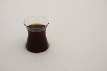 Traditional Turkish black tea (çay or cay) in a typical clear glass on the snow in Turkey during the winter 2021