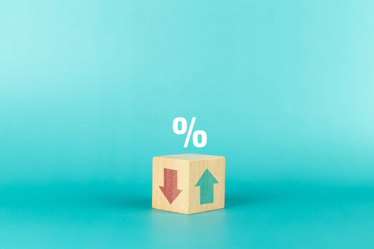 Wooden cube with Down arrow and UP arrow and percentage symbol on blue background. Concept of financial, stocks and interest rate