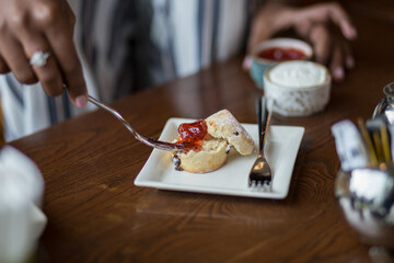 A scone topped with strawberry jam and whip cream
