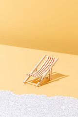 Fototapeta na wymiar A red striped beach chair for sunbathing on a yellow background and paper waves Summer and holiday concept. vertical image with copy space