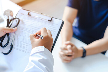 Close-up of a male doctor hand hold a silver pen and showing pad in hospital. Doctor giving...