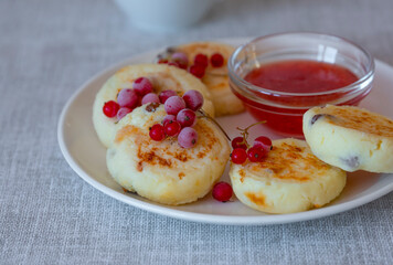 A healthy breakfast of cottage cheese pancakes, syrniki with red currants and close-up in a plate on the table. light background